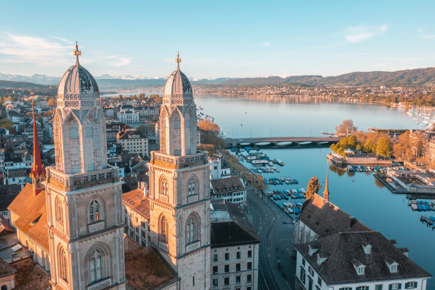 Blick über die Stadt Zürich mit dem Grossmünster links im Vordergrund und Ausblick auf den Zürichsee im Hintergrund.