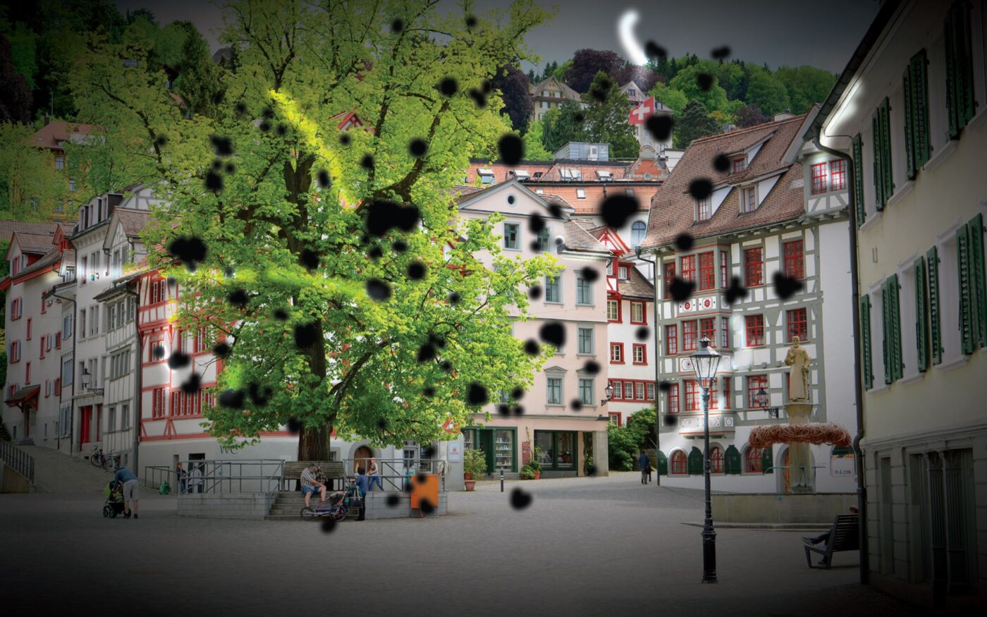 Image d'une vieille ville avec des maisons et un grand arbre au premier plan. Des taches noires et des filaments flottent dans le champ visuel et rendent la vision difficile.