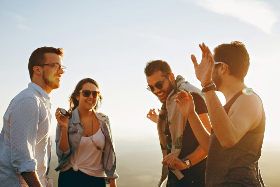 Drei junge Männer und eine junge Frau, die miteinander sprechen und lachen