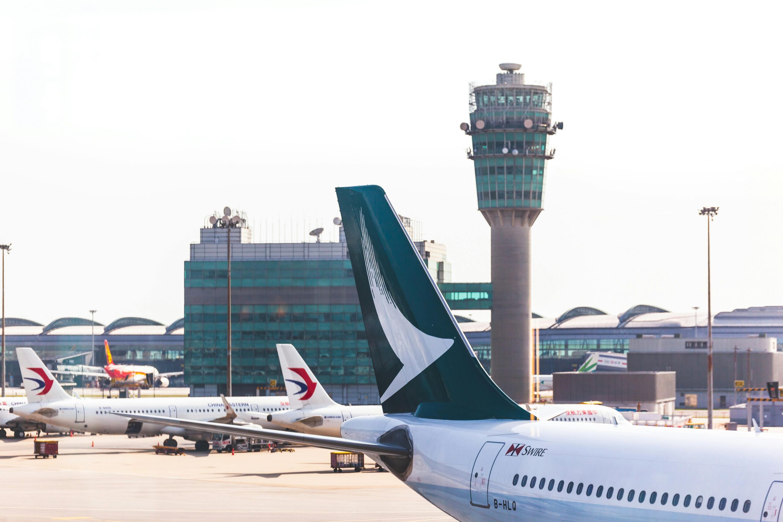Flughafen mit Blick auf den Kontrollturm. Im Vordergrund sind drei Flugzeuge zu sehen.