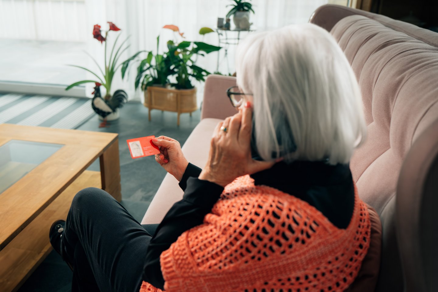 Frau mit SwissPass in der Hand telefoniert im Wohnzimmer mit der ZVV-Kontaktstelle