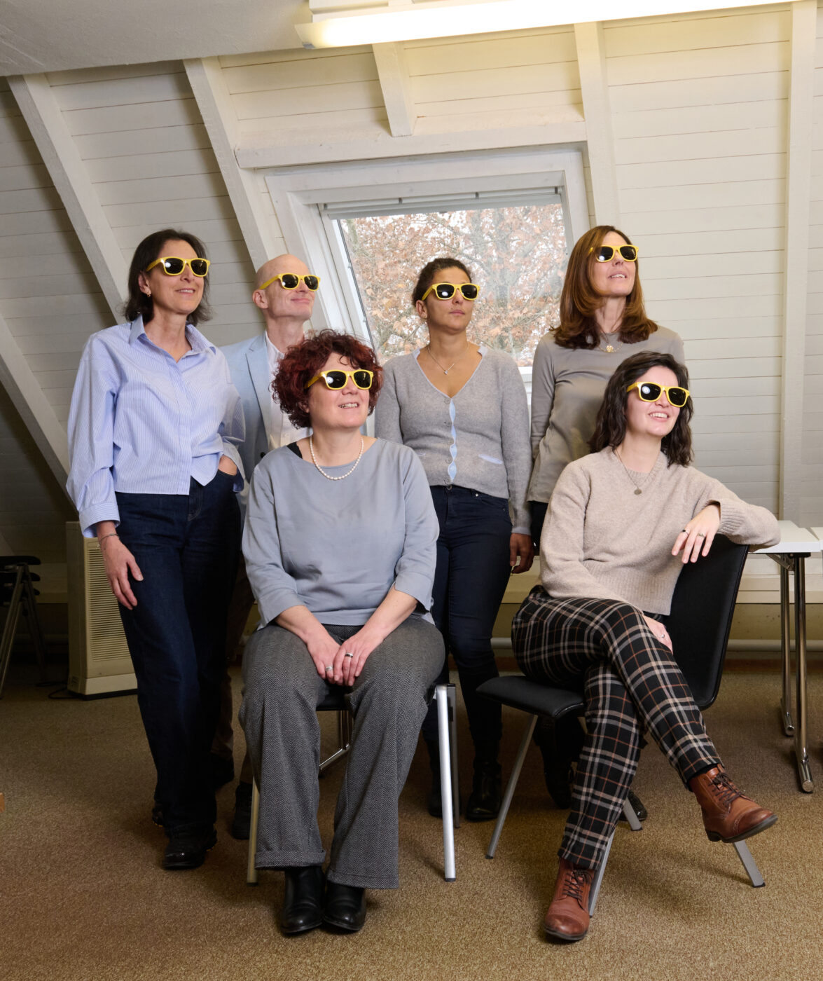 I collaboratori e la diretrice Susanne Trudel guardano insieme confidenti al futuro. Tutti indossano occhiali da sole gialli.