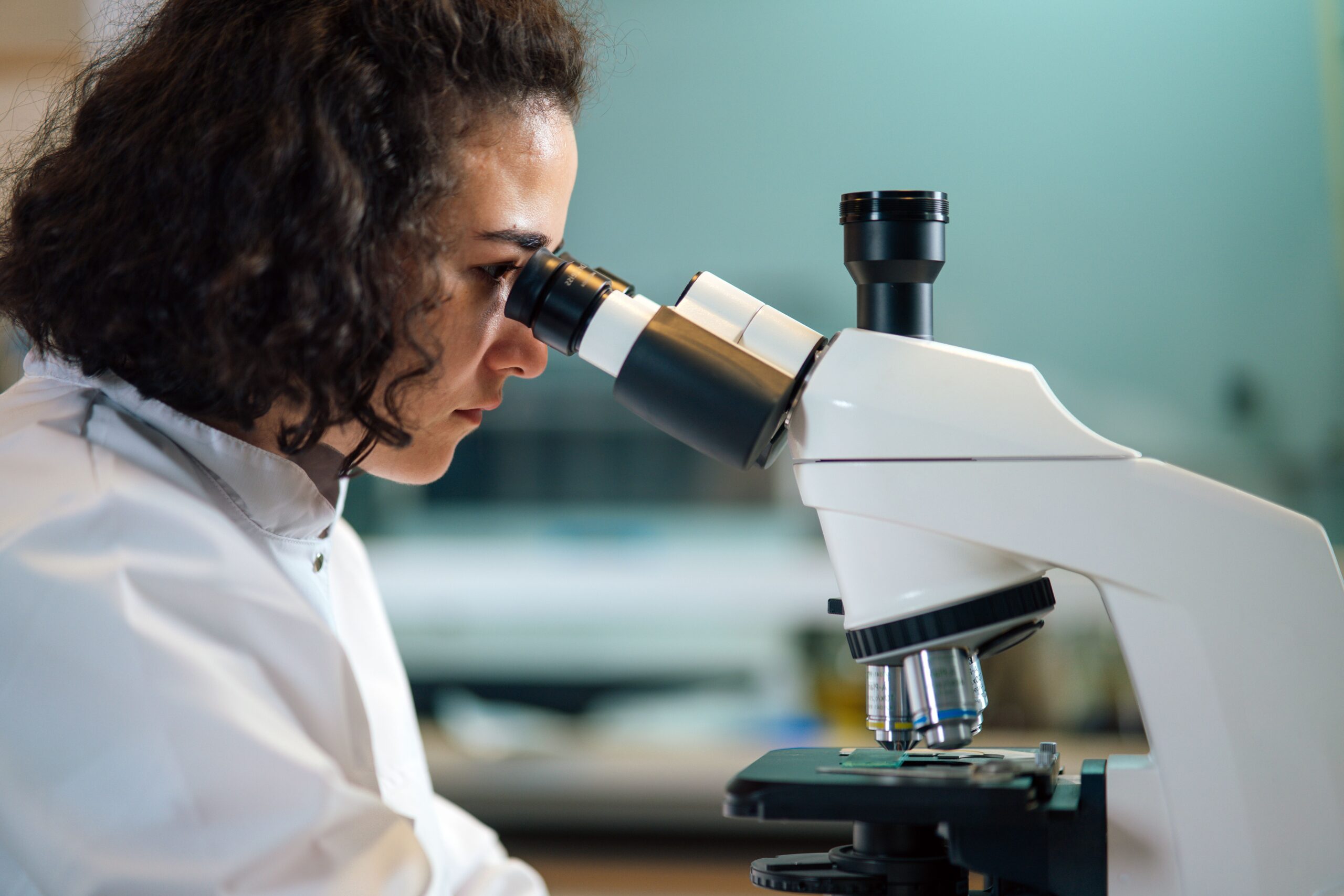 Une femme aux cheveux foncés regarde dans un microscope